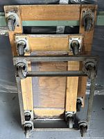 Top down view of three furniture dollies showing wooden platforms and metal caster wheel mounts.