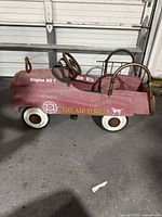 Side view of the red fire truck pedal car showing decals and overall body condition