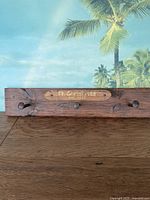 Front view of rustic wood coat rack mounted with 3 railroad spikes and text plaque 'Ft Christmas est. 1837'.