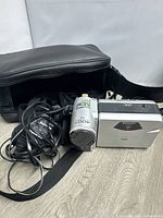 Silver Sharp Viewcam Hi8 handheld video cassette recorder with cables, remote, and carrying case on floor.