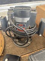 Top-down and front views highlighting the Skil brand label and model 1835 on the plunge router with power cord coiled around the device.