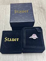 Image showing Stauer branded textured blue box and black velvet ring box with ring inside.