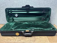 Full open view of the black Travelight violin case showing green velvet interior and bow holders.