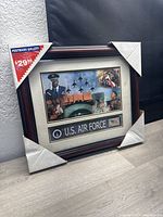 Framed U.S. Air Force commemorative art in original condition with protective corner covers and label showing retail price $29.95