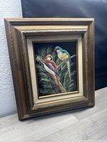 Overall view of the framed painting showing two tropical birds perched on a branch with greenery in the background.