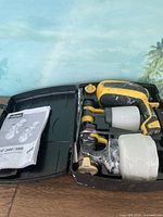 Paint sprayers and carrying case showing sprayers with paint containers attached and instruction manual inside case.