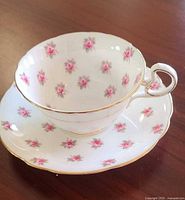 Teacup on saucer showing rose pattern and gilt trim