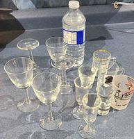Group of six stemmed glasses and four shot glasses on countertop