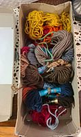 Open box filled with various coloured partial skeins of wool yarn