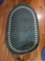 Full overhead view of green oval braided rug on hardwood floor