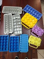 Assorted ice cube trays, egg molds and egg container on table
