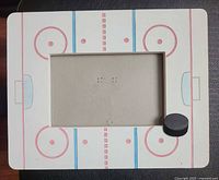 Front view of hockey rink themed photo frame showing rink markings and black puck accent