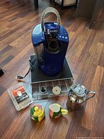 All items grouped: Keurig brewer on storage drawer, reusable pod, filter sleeves, decanter, creamer, sugar bowl