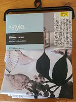 Front of packaged InStyle black and white polyester shower curtain showing size 71x71 in and botanical pattern