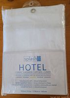 Front of sealed Splash Home Hotel fabric shower curtain liner package