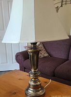 Full view of brass-tone table lamp with square shade on table