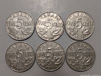 Top view of six 1931 Canadian nickels dated 'FIVE 5 CENTS' with leaves on front side.