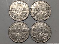 Four Canadian five cent coins dated 1932 showing the reverse side with denomination and maple leaves.