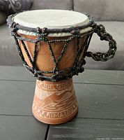 Photo shows a carved wooden drum from Hawaii about 8 inches tall with a natural drumhead and colorful braided rope tension system.