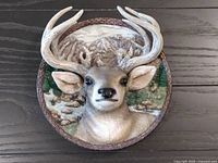 Front view of the round collector plate with a three-dimensional deer head and nature scene background.