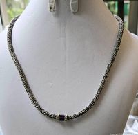 Front view of the full silver-toned woven chain necklace with purple stone pendant.