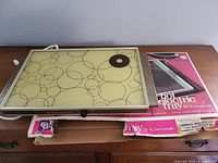 Full view of Cornwall Electro Glass Hot Electric Warming Tray laid on its original box on wooden surface.