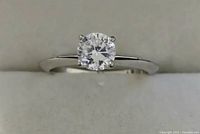 Front view of silver-toned ring with clear round stone in a prong setting.