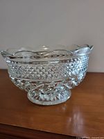 Front view of clear glass serving bowl showing scalloped rim, decorative cut diamond and lattice pattern on body, and pedestal base.