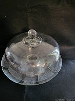Close-up of glass dome lid for cake stand highlighting its clarity and knob handle.