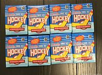 Photo of eight unopened 1991-92 O-Pee-Chee hockey card packs arranged in two rows of four, showing front packaging with blue, yellow, and red colors and hockey-themed design.