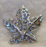 Front view of the maple leaf brooch showing its rhinestones and silver-tone metal detailing.