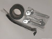 Photo showing three new adjustable wrenches sealed in plastic, a pry bar also sealed in plastic, and a partially used roll of black duct tape.