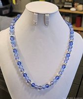 Photo of full blue and light purple beaded necklace displayed on a white bust stand showing length and bead style.