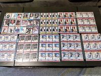 Wide angle photo showing 90 Wayne Gretzky hockey cards laid out in rows on table, including various editions and designs.