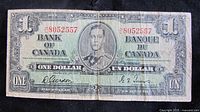 Front view of the 1937 Bank of Canada one dollar note showing portrait of King George VI and signatures of Governor Gordon Towers and Deputy Governor G.F. Towers, prefix and serial number H/L 8052557.