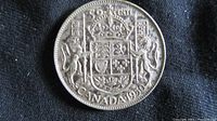 Reverse of 1950 Canadian 50 cent coin showing detailed Canadian coat of arms and denomination.