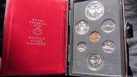 Royal Canadian Mint red display case opened showing 1974 commemorative coins in protective slots.