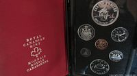 Photo of opened red Royal Canadian Mint case showing the coin set including the large commemorative silver dollar.