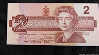 Front side of 1986 two dollar Canadian banknote showing Queen Elizabeth II portrait, signatures, and denomination.