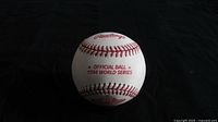 Photo showing Rawlings logo and text 'OFFICIAL BALL 1994 WORLD SERIES' stamped in red on white baseball leather with red stitching.