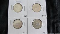 Four Canadian 1967 quarters displayed with reverse side showing different animal designs for the centennial celebration.