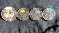 Obverse side showing detailed colour designs of 2023 Toonie and three 2011 quarters with wildlife themes