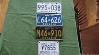 Four Ontario license plates from 1973 to 1976 including a smaller school vehicle plate