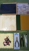 Overview of various stained glass sheets and mosaic pieces alongside some tools.