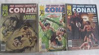 Front covers of three Conan comic issues lying side by side on a surface.