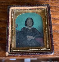 Full view of cabinet photo showing young girl, gold frame, and worn protective case