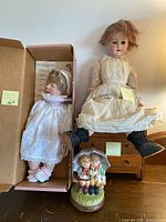 Photo showing antique French Middleton doll in white dress in box, antique oak doll dresser, and musical figurine in front.