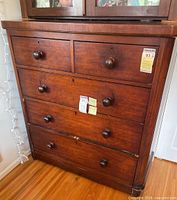 Front view of dresser showing five drawers with wooden knobs and overall finish