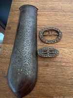 Full view of iron arm band and two buckles on table