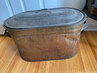 Large antique copper wash tub with lid, showing its rectangular rounded shape and patina.